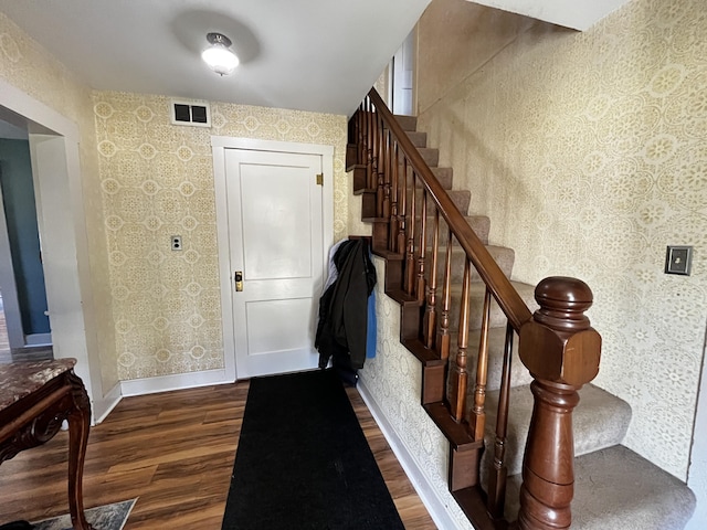 entrance foyer with wallpapered walls, visible vents, baseboards, stairway, and wood finished floors