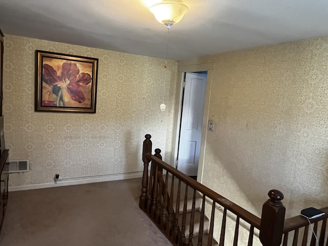 hallway featuring visible vents, carpet, an upstairs landing, and baseboards