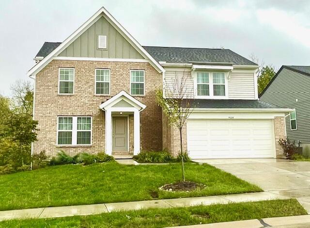 view of front of property featuring an attached garage, brick siding, driveway, a front lawn, and board and batten siding