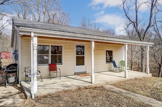 rear view of house with a shingled roof and a porch