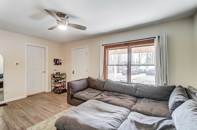 living area with ceiling fan, light wood-style flooring, and baseboards