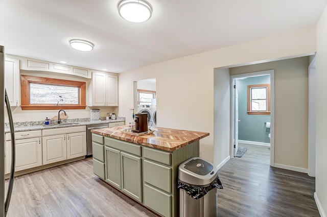 kitchen featuring light wood-style flooring, wood counters, stainless steel appliances, separate washer and dryer, and a sink