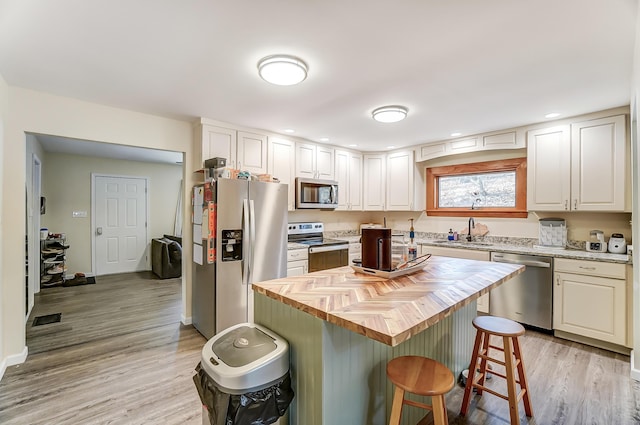 kitchen with visible vents, appliances with stainless steel finishes, a sink, butcher block countertops, and a kitchen breakfast bar