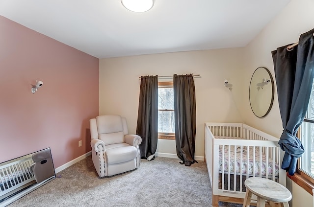 carpeted bedroom featuring heating unit, a nursery area, and baseboards