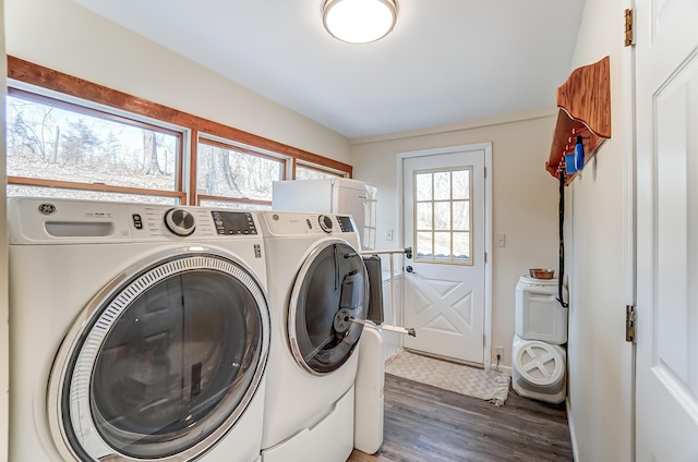 clothes washing area featuring laundry area, washer and clothes dryer, and wood finished floors