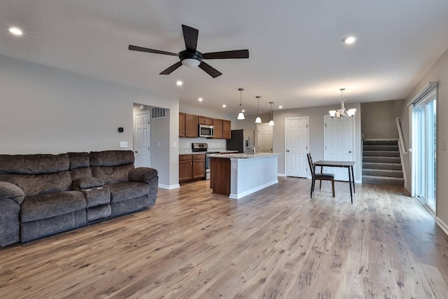 living area with light wood-style floors, ceiling fan with notable chandelier, visible vents, and recessed lighting