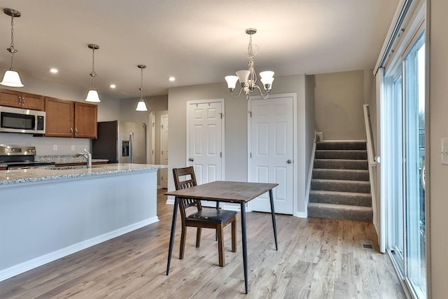 kitchen featuring light wood-type flooring, appliances with stainless steel finishes, brown cabinetry, and a sink