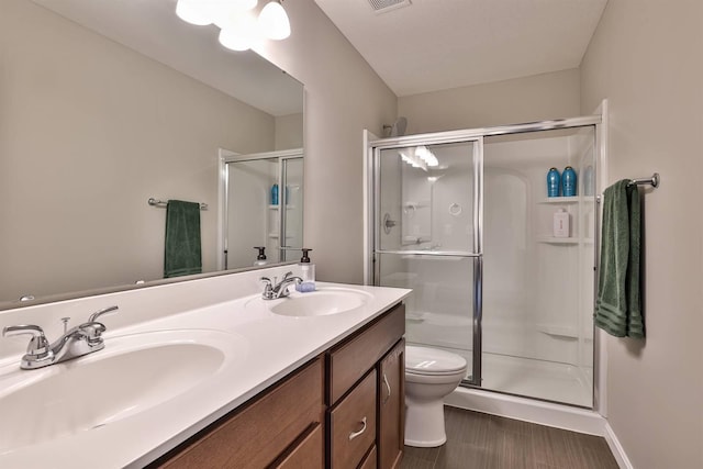 bathroom with a sink, a shower stall, toilet, and double vanity