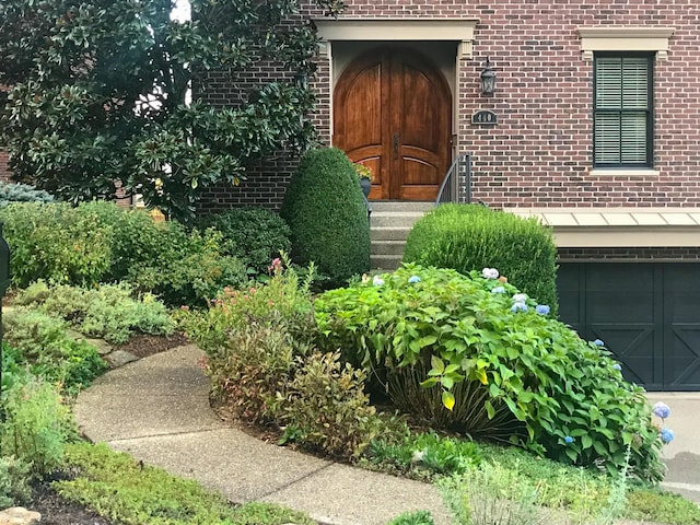 view of exterior entry with a garage and brick siding