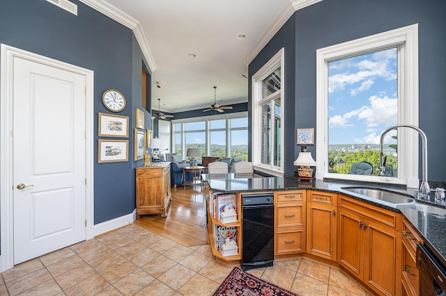 kitchen with black dishwasher, brown cabinets, dark stone countertops, crown molding, and a sink