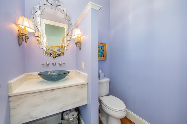 half bath featuring toilet, baseboards, and vanity