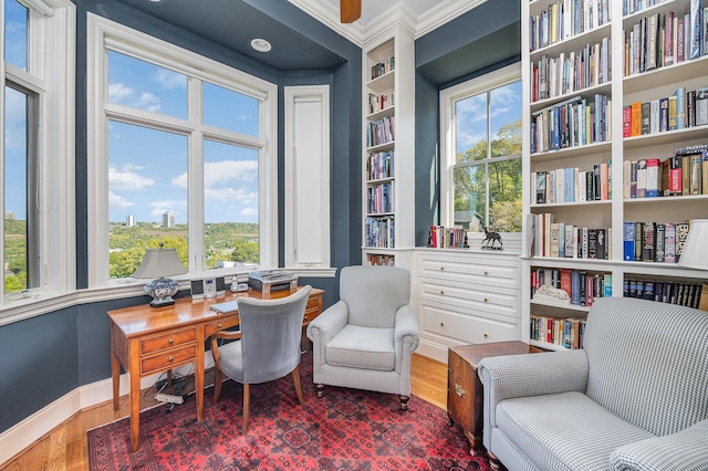 home office with ornamental molding, built in shelves, baseboards, and wood finished floors