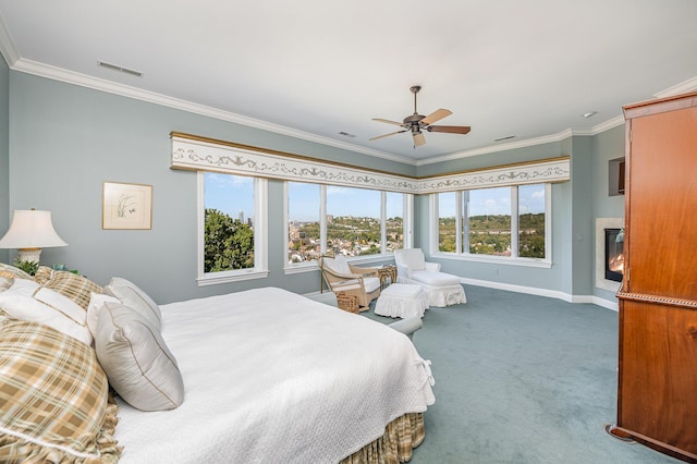 carpeted bedroom featuring baseboards, visible vents, crown molding, and a glass covered fireplace