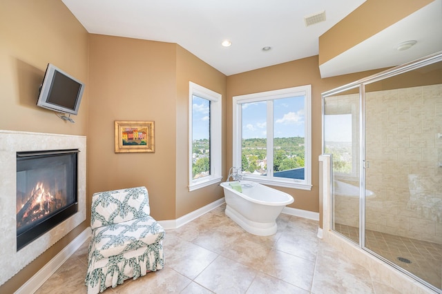 full bath with visible vents, baseboards, a soaking tub, a shower stall, and a fireplace