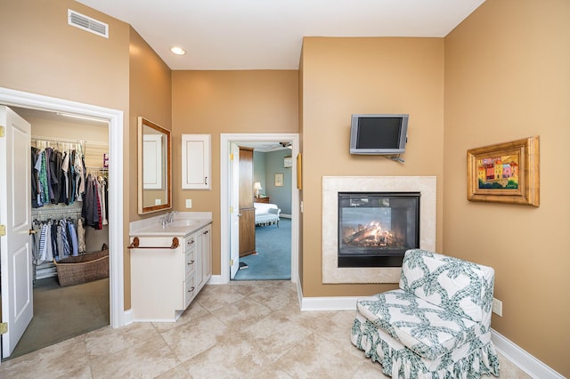 sitting room featuring light tile patterned floors, baseboards, visible vents, and a glass covered fireplace