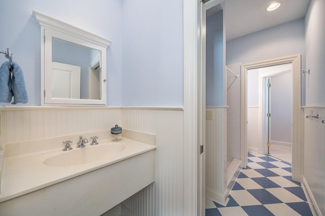 bathroom with a wainscoted wall, a shower stall, vanity, and tile patterned floors