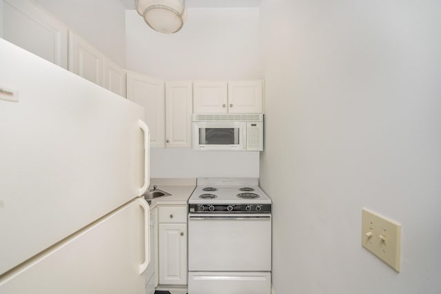 kitchen featuring light countertops, white appliances, and white cabinets