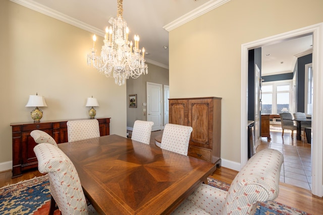 dining space with a chandelier, ornamental molding, wood finished floors, and baseboards