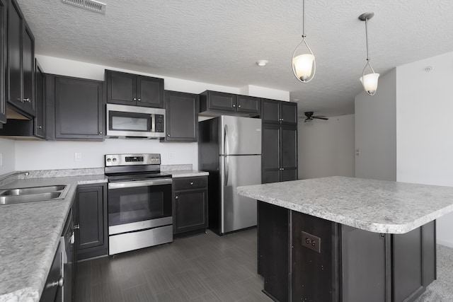 kitchen with stainless steel appliances, a kitchen island, a sink, and light countertops