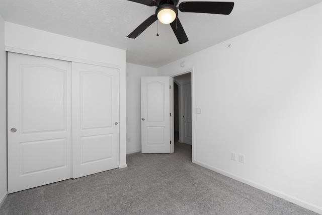 unfurnished bedroom featuring carpet floors, a closet, a ceiling fan, a textured ceiling, and baseboards