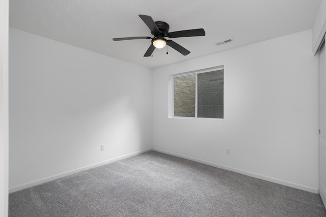 spare room with ceiling fan, carpet floors, visible vents, and baseboards