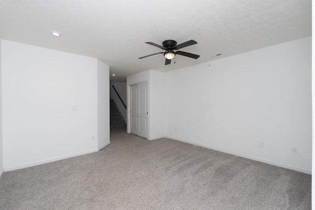 empty room featuring a textured ceiling, baseboards, a ceiling fan, and light colored carpet