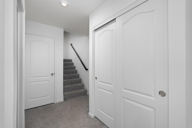 hallway with carpet, stairway, and a textured ceiling