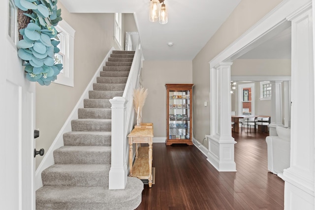 foyer entrance with baseboards, decorative columns, stairway, and dark wood-style flooring