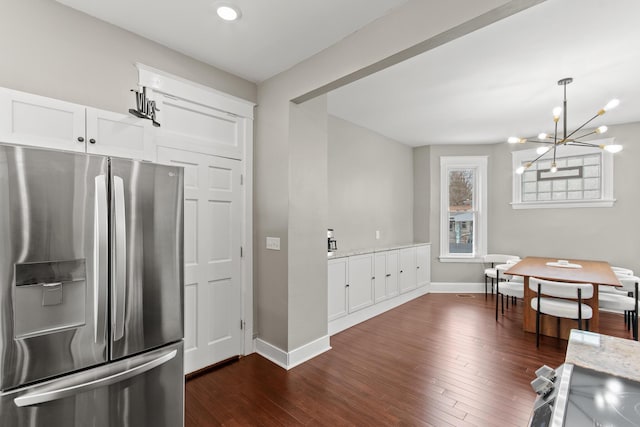 kitchen with stainless steel fridge, dark wood finished floors, baseboards, and white cabinetry