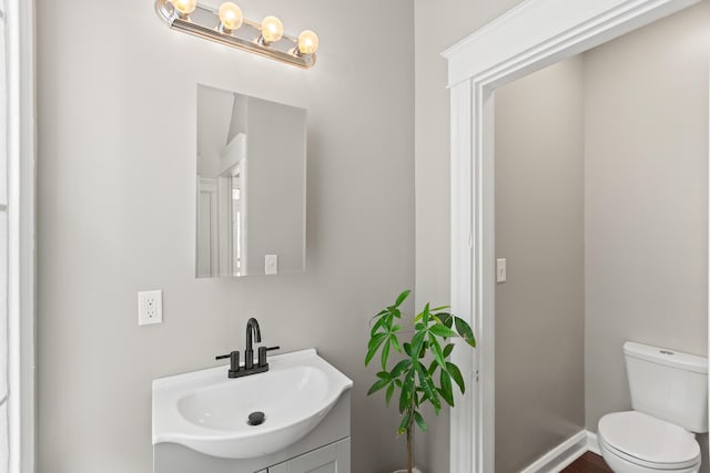 half bath with vanity, toilet, and baseboards