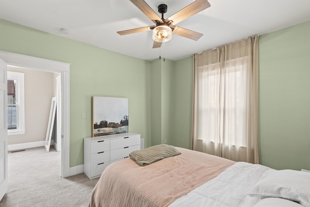 bedroom with a ceiling fan, light colored carpet, visible vents, and baseboards