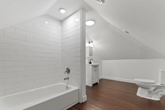 bathroom featuring toilet, lofted ceiling, wood finished floors,  shower combination, and vanity