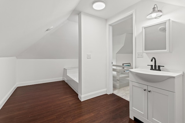 bathroom featuring lofted ceiling, vanity, baseboards, and wood finished floors