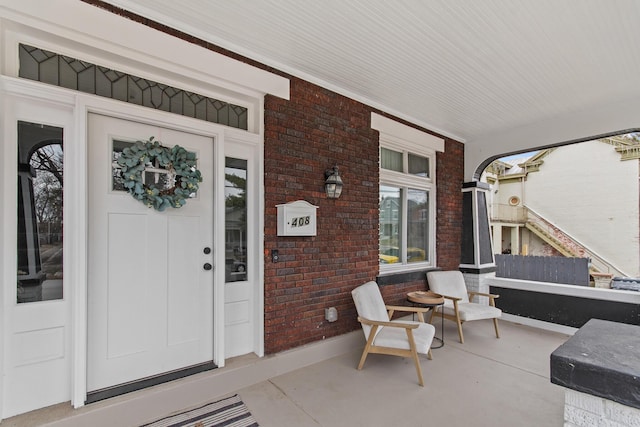 doorway to property with a porch and brick siding