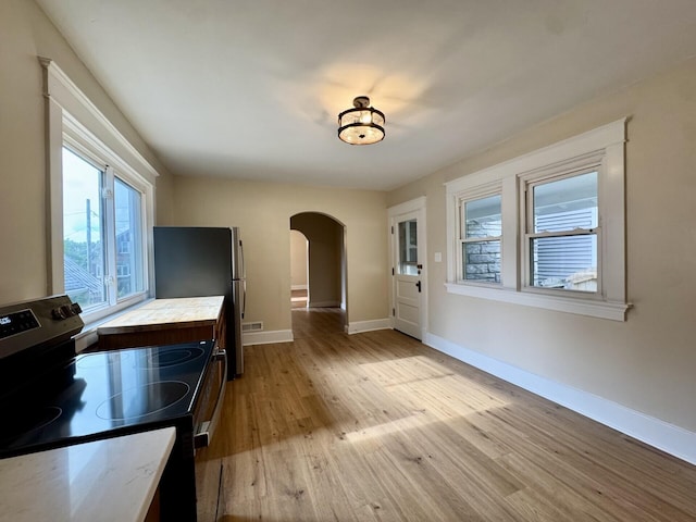 1307 Highway Ave, Covington, KY 41011 - unfurnished dining area featuring arched walkways, plenty of natural light, and light wood-type flooring