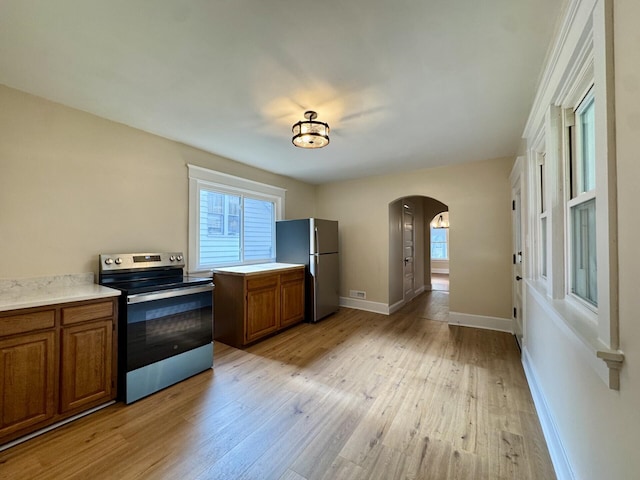 1307 Highway Ave, Covington, KY 41011 - kitchen with stainless steel appliances, brown cabinets, arched walkways, and light wood-type flooring