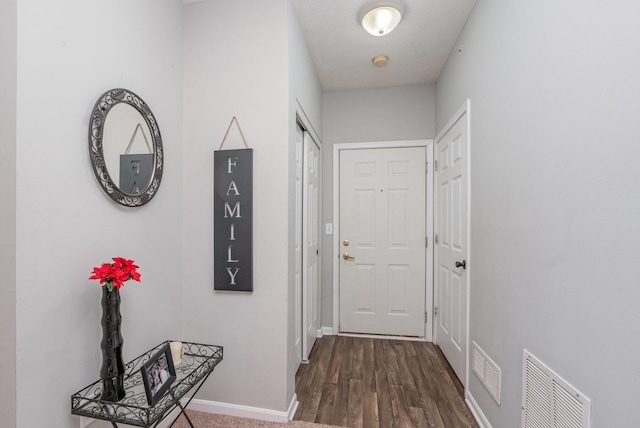 entryway with baseboards, visible vents, and dark wood-type flooring