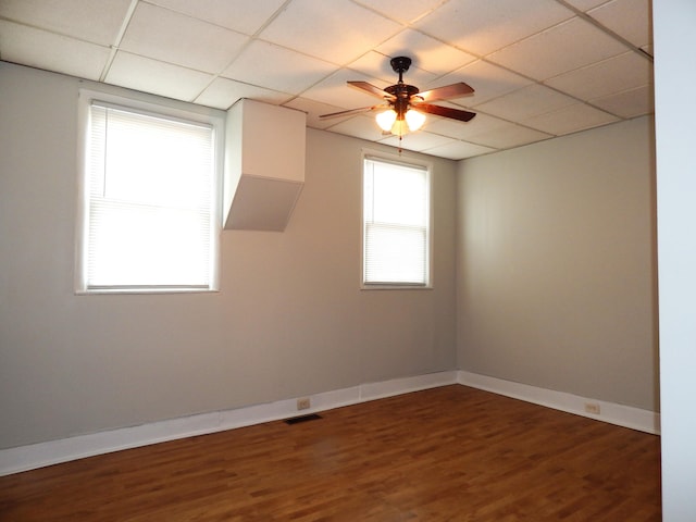 empty room featuring baseboards, visible vents, a drop ceiling, and wood finished floors