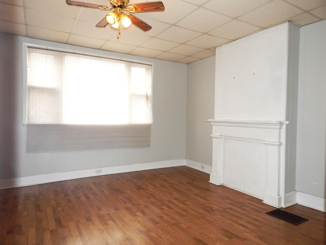 unfurnished room featuring baseboards, visible vents, ceiling fan, wood finished floors, and a paneled ceiling