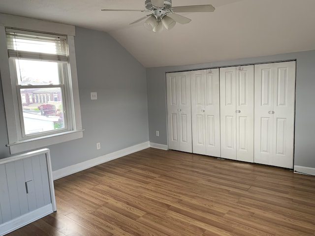 unfurnished bedroom featuring baseboards, a ceiling fan, radiator, wood finished floors, and vaulted ceiling