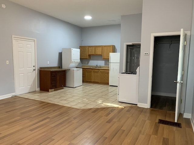 kitchen featuring light wood finished floors, stove, a sink, and freestanding refrigerator