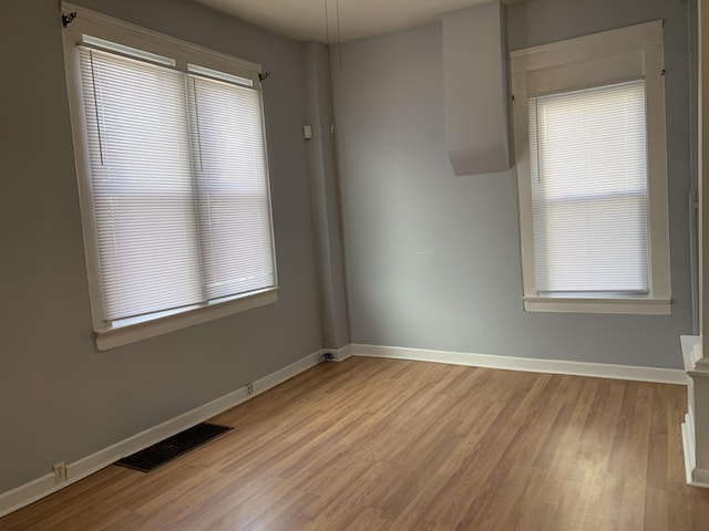 spare room with visible vents, baseboards, and wood finished floors