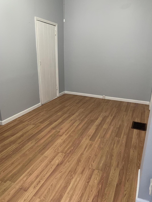 empty room with light wood-style flooring, visible vents, and baseboards