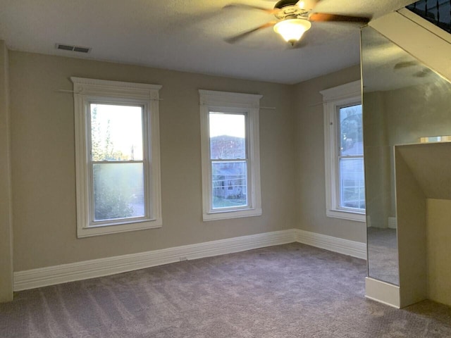 spare room featuring ceiling fan, carpet flooring, visible vents, and baseboards