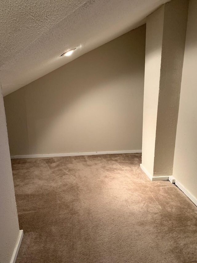 interior space with a textured ceiling, a textured wall, carpet, and baseboards