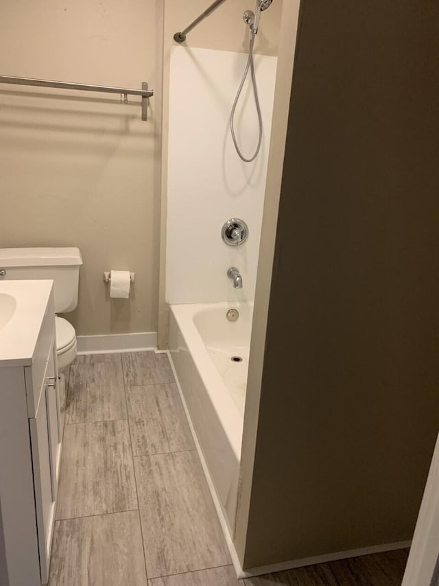 bathroom featuring bathtub / shower combination, vanity, toilet, and baseboards