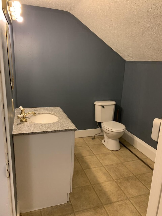 half bath with a textured ceiling, toilet, vanity, and baseboards