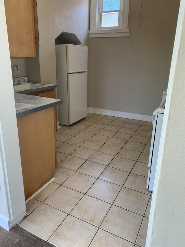 kitchen with baseboards, light tile patterned flooring, and freestanding refrigerator