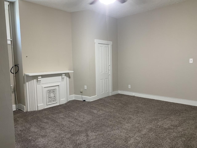 unfurnished room with dark carpet, baseboards, and ceiling fan