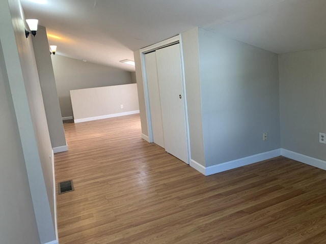 bonus room featuring visible vents, baseboards, vaulted ceiling, and wood finished floors